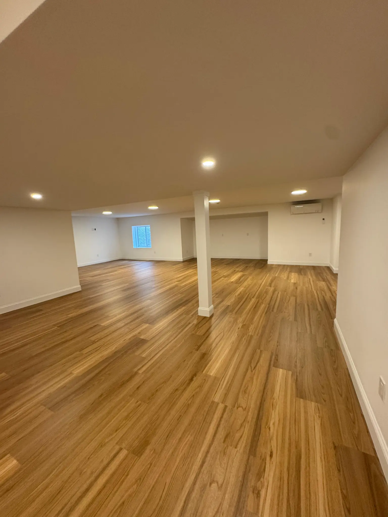 Open basement with hardwood LVP flooring and recessed lighting by Regulus Construction