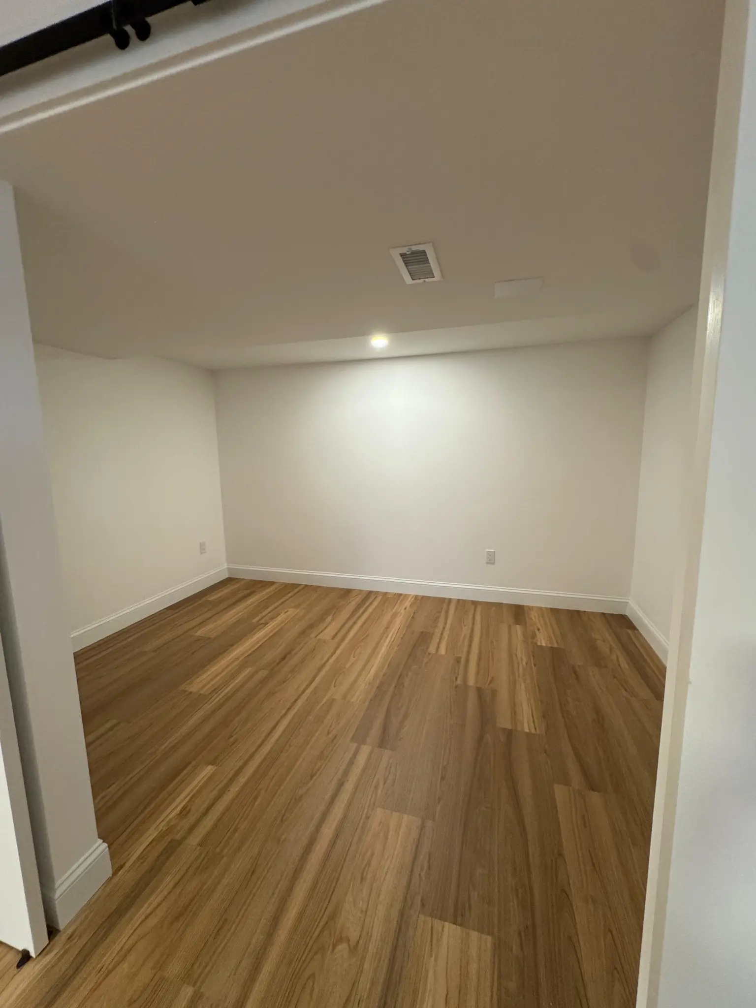 Finished basement room with hardwood flooring and recessed lighting by Regulus Construction