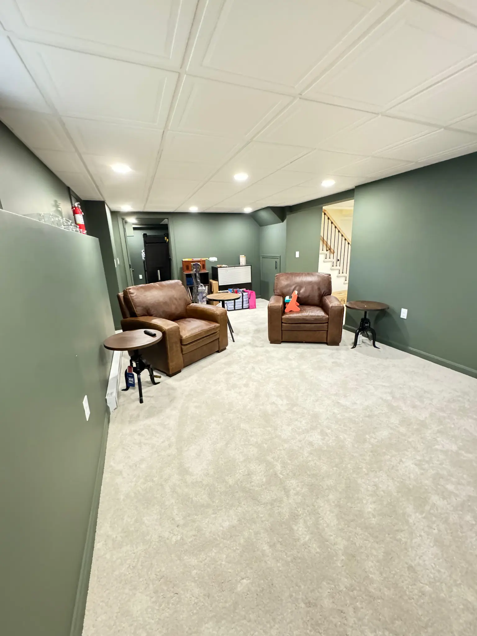 Finished basement lounge with leather recliners and staircase by Regulus Construction