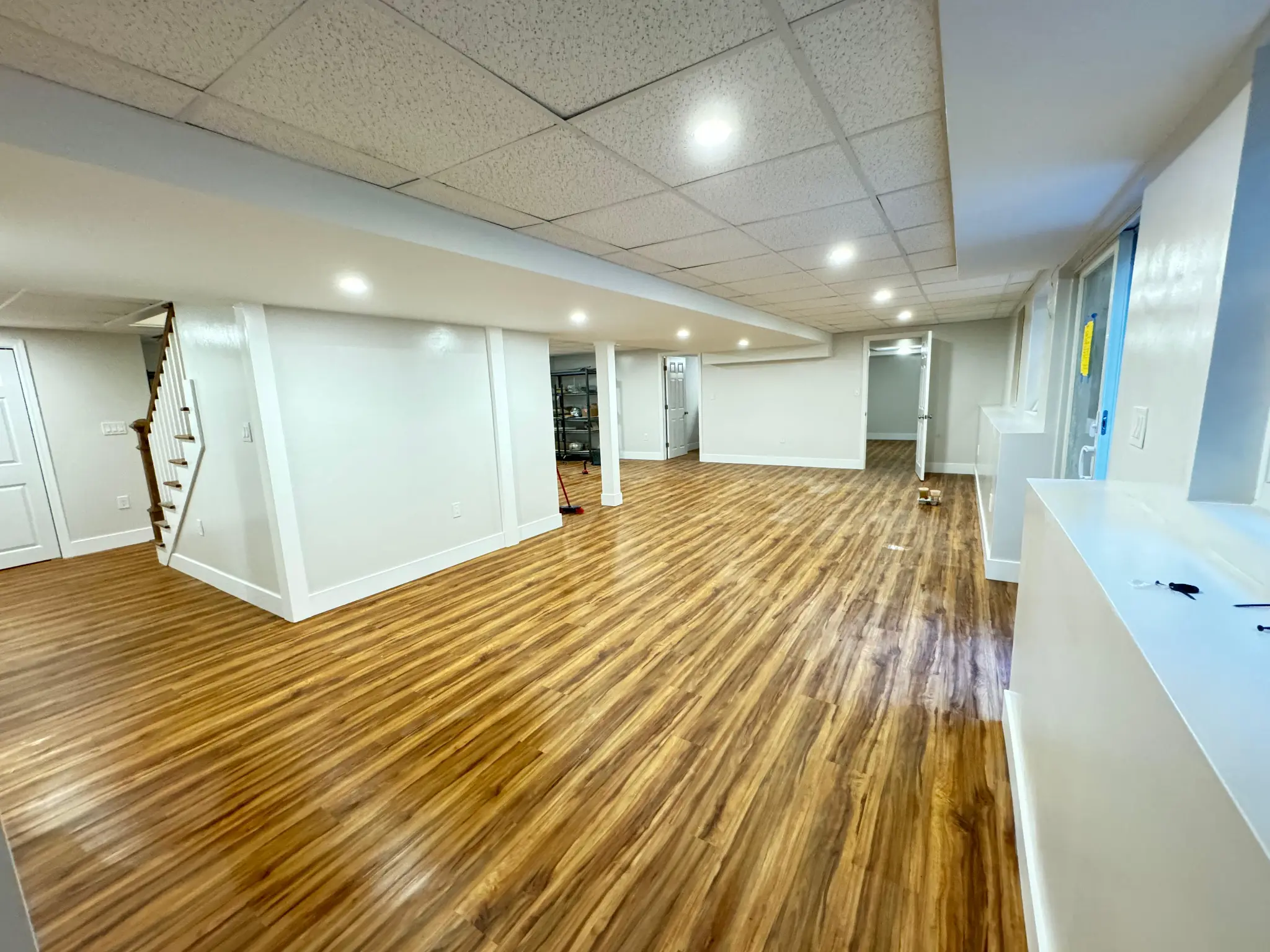 Large finished basement with hardwood flooring staircase and countertop by Regulus Construction